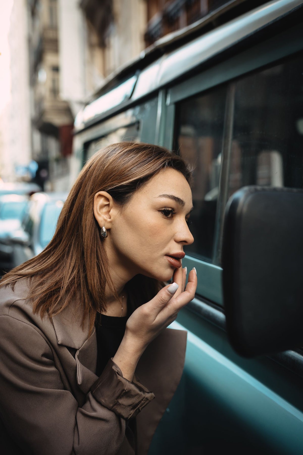 Mujer revisándose el pelo en el espejo del coche antes de una cita